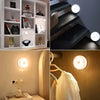 A set of motion sensor LED night lights illuminating a white cabinet and a dark staircase.