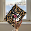 A leopard print protective cover for an iPad is held up against a window with a snowy background.