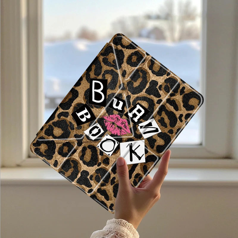 A leopard print protective cover for an iPad is held up against a window with a snowy background.