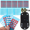 A hand holds a blue plastic sheet with red and white round dots, demonstrating the glide feet for a universal mouse.