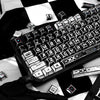 A close-up of a black and white comic-style PBT keycap set on a mechanical keyboard, viewed from above.