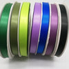 Sammlung von doppelseitigen Satinbandrollen in verschiedenen Farben wie grün, oliv, limettgrün, lila, blau und schwarz.