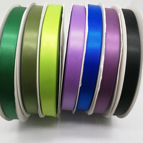 Sammlung von doppelseitigen Satinbandrollen in verschiedenen Farben wie grün, oliv, limettgrün, lila, blau und schwarz.