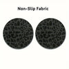 A set of two black non-slip fabric coasters with a leopard print design.