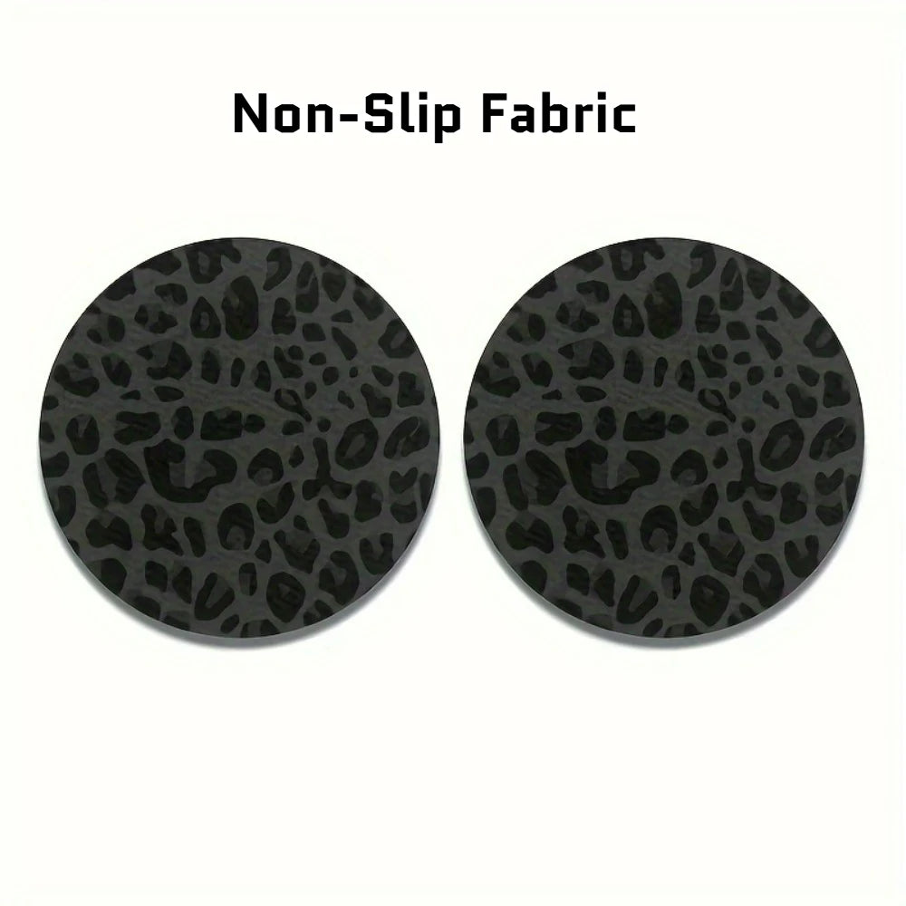 A set of two black non-slip fabric coasters with a leopard print design.