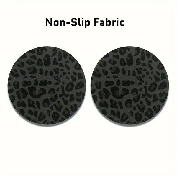 A set of two black non-slip fabric coasters with a leopard print design.