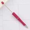 A pink DIY beadable pen with a silver band and a black ink tip resting on a white surface.