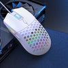 A white optical wired gaming mouse with a perforated shell and colorful RGB lighting is shown on a dark surface.