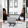 A woman is using a USB-C docking station with an adjustable laptop stand on a white desk.