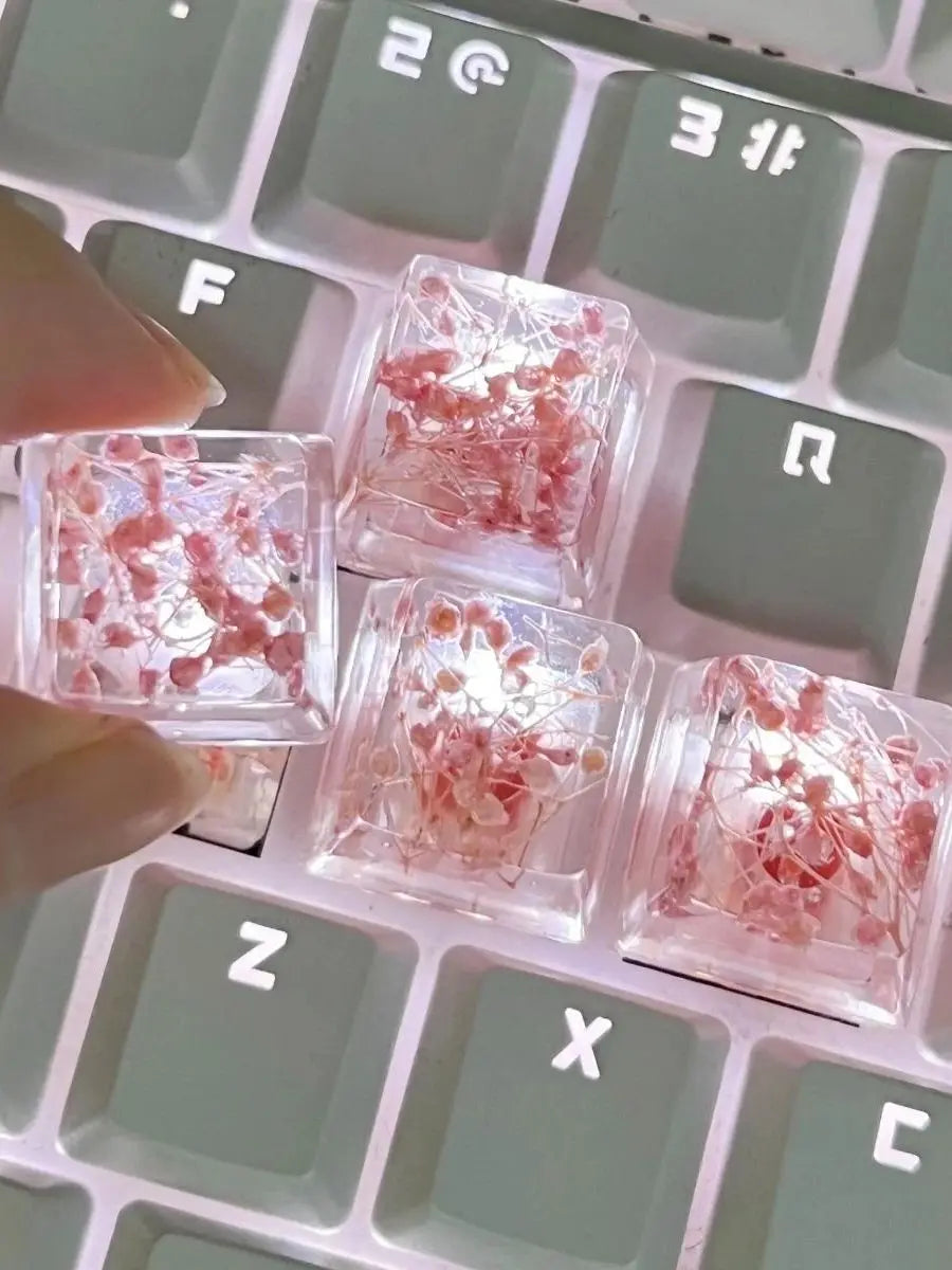 Close-up of translucent pink botanical resin keycaps resting on a mechanical keyboard.