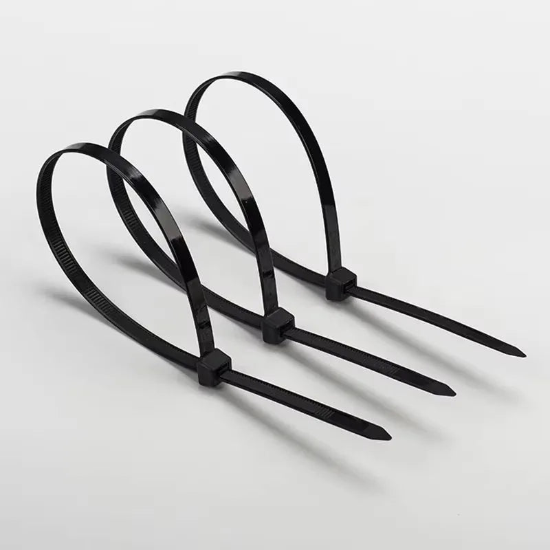 Three black heavy-duty nylon cable ties with self-locking design laid out on a white surface.