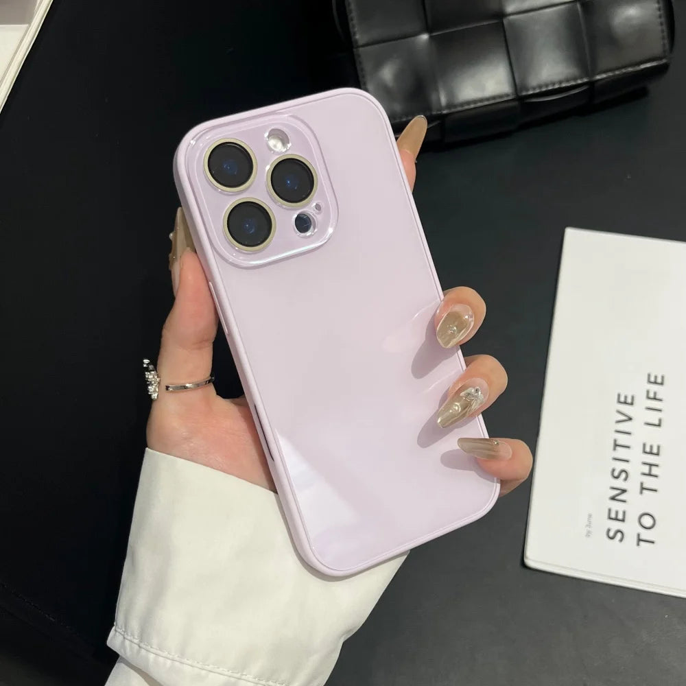 A hand holds a light purple iPhone with a clear case, displaying the camera module and back design.