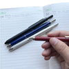 A hand holds a collection of four pens, including a ballpoint pen and a mechanical pencil, resting on a dated planner page.