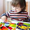 A young child is using decorative zig zag edge scissors to cut colorful paper for a craft project.