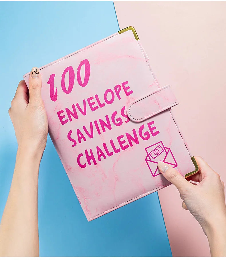 A pink marble budget binder is shown being held by a hand, featuring the text 100 Envelope Savings Challenge.