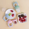 A silicone fruit and vegetable feeder set for babies and toddlers showing various colored fruits like tomatoes and olives.
