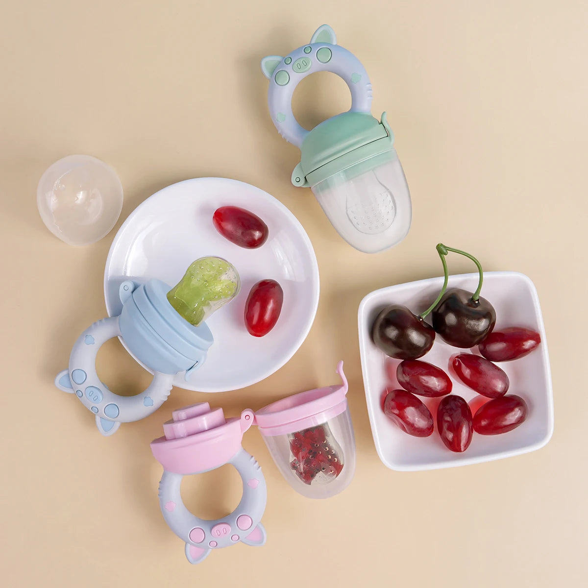 A silicone fruit and vegetable feeder set for babies and toddlers showing various colored fruits like tomatoes and olives.
