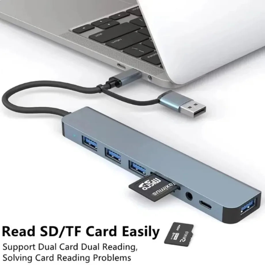 A silver USB-C hub with multiple SD/TF card slots and an audio jack connected to a laptop.