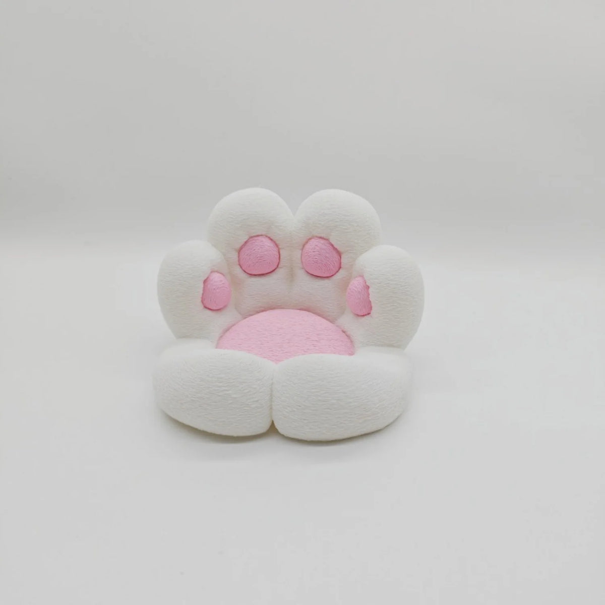 A white, soft cat paw shaped phone stand with pink accents and an anti-slip base.