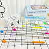Un juego de cinco punteros retráctiles de profesor plateados con puntas de colores sobre un paño a cuadros blanco y negro.