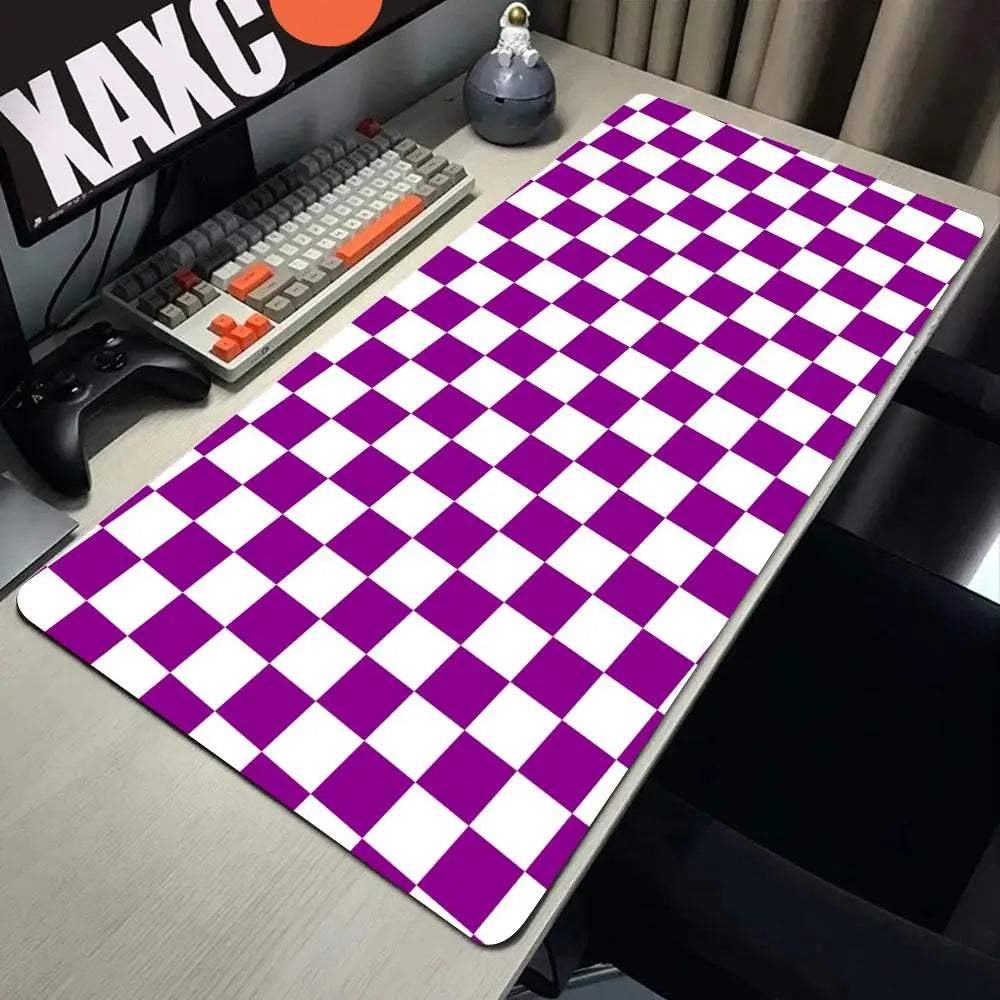 A purple and white checkered desk mat is displayed on a wooden table next to a keyboard and gaming controller.