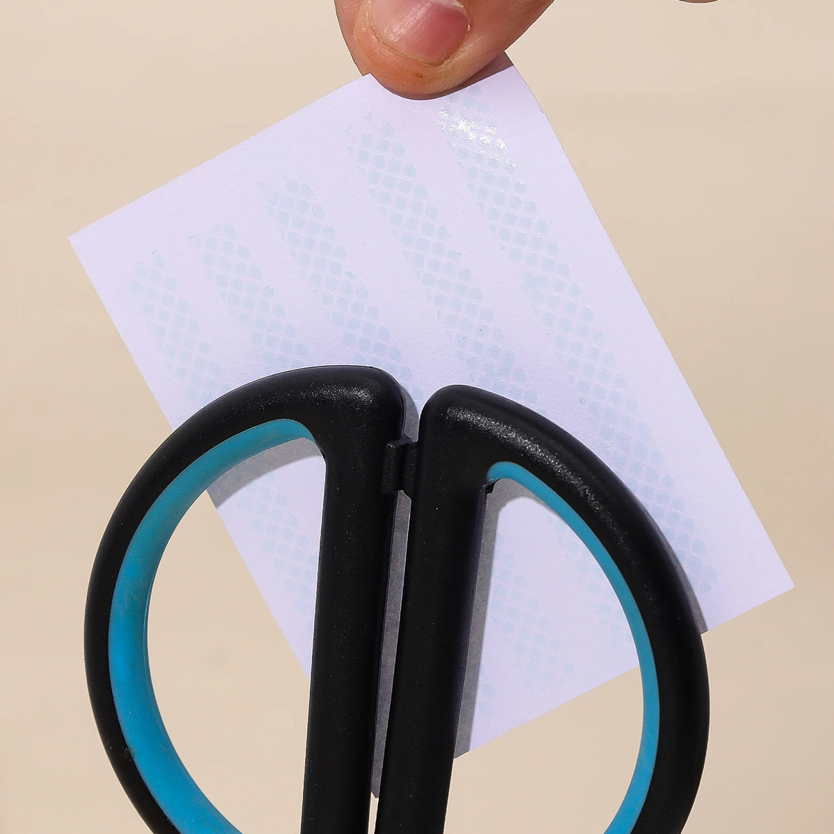 A hand is holding a black gradient double-sided tape pen over a white piece of paper.
