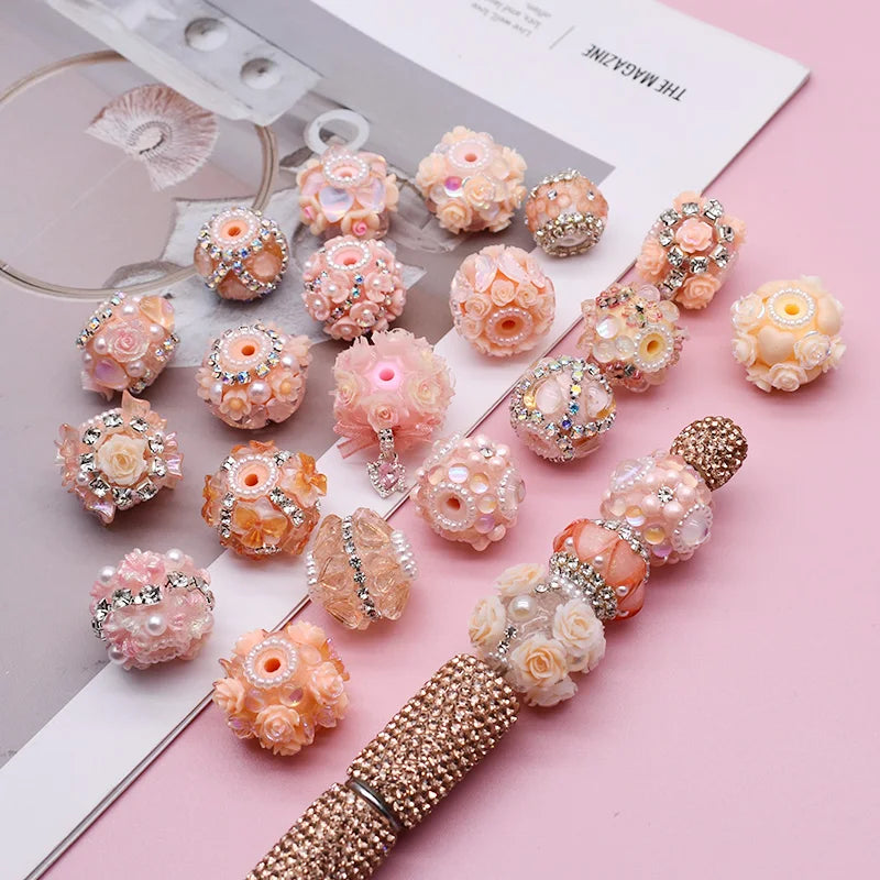 A collection of pink and gold acrylic flower beads and findings for jewelry making displayed on a white card.