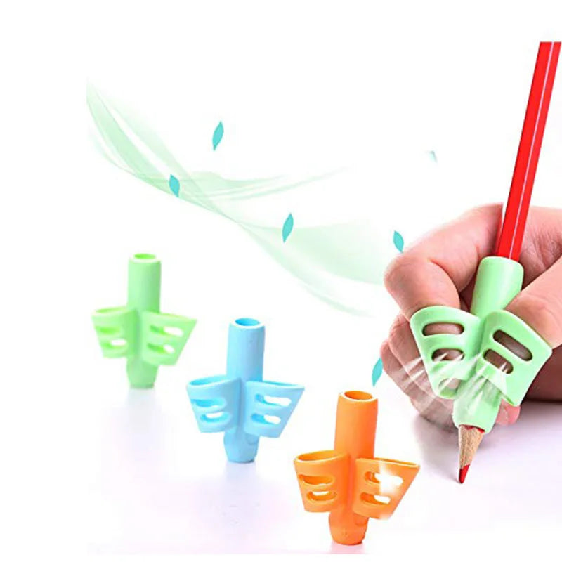 Hand holding an orange silicone pencil grip, with green and blue grips scattered in the background.