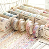 A collection of five rolls of floral washi tape in various patterns displayed in cardboard boxes.