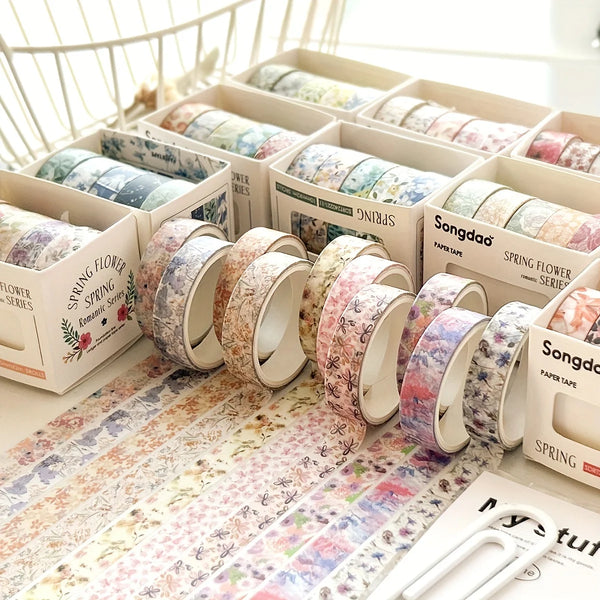 A collection of five rolls of floral washi tape in various patterns displayed in cardboard boxes.