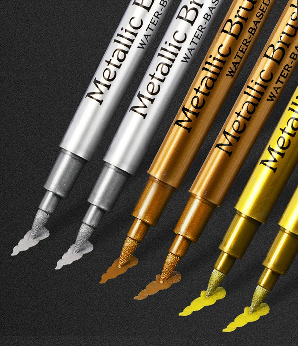 A close-up view of several metallic brush marker pens in various colors and finishes.