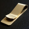 A vintage solid brass money clip with a card holder shown in profile against a dark background.