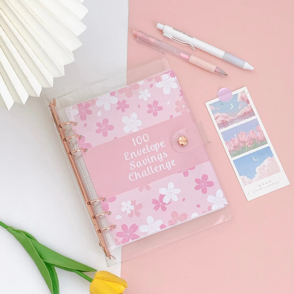 A pink A5 envelope budget binder set with a pink cover and a pencil resting on a light pink background.