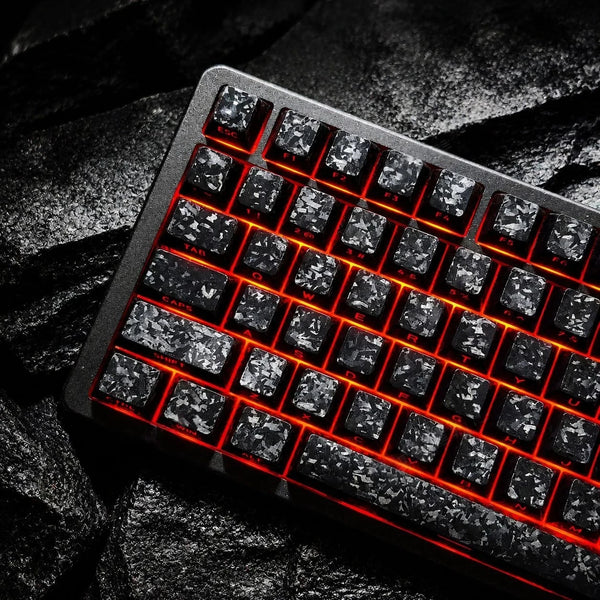 A close-up shot of a black mechanical keyboard with carbon pattern keycaps illuminated by red backlighting.