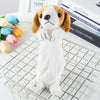A white plush dog figurine with brown floppy ears and black eyes sitting on a white wire mesh tray.