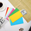 A collection of colorful cash envelopes and a stack of paper on a white surface.