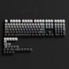 A close-up view of a gradient PBT keycap set for mechanical keyboards arranged on a dark surface.