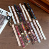 A collection of resin beaded watch bands in various colors and patterns laid out on a wooden surface.