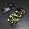 A black iPhone case featuring a leopard print camouflage pattern, placed next to a silver phone grip.