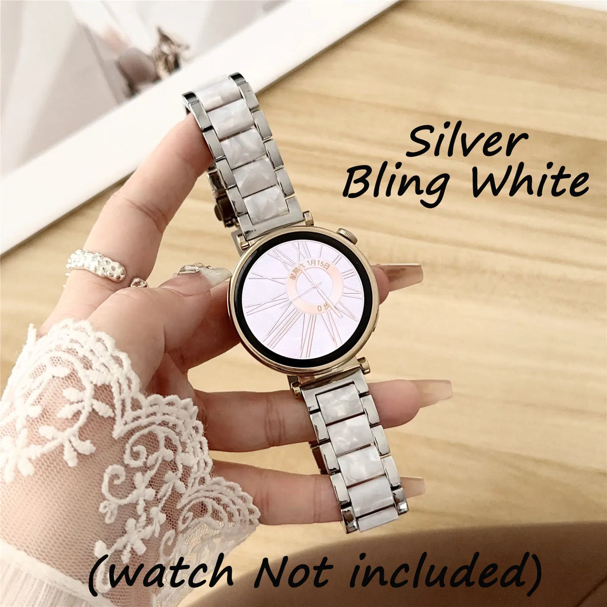 Eine Hand hält eine silberne, glitzernde weiße Uhr mit einem hellen Harzband und einer weißen Zifferblatt auf einem Holz-Hint