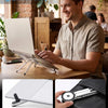 A man is using a laptop companion mount to hold a silver laptop and a smartphone on a wooden table.