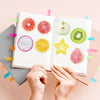 A set of fruit-shaped sticky notes including watermelon, grapefruit, orange, and kiwi slices on a white pad.