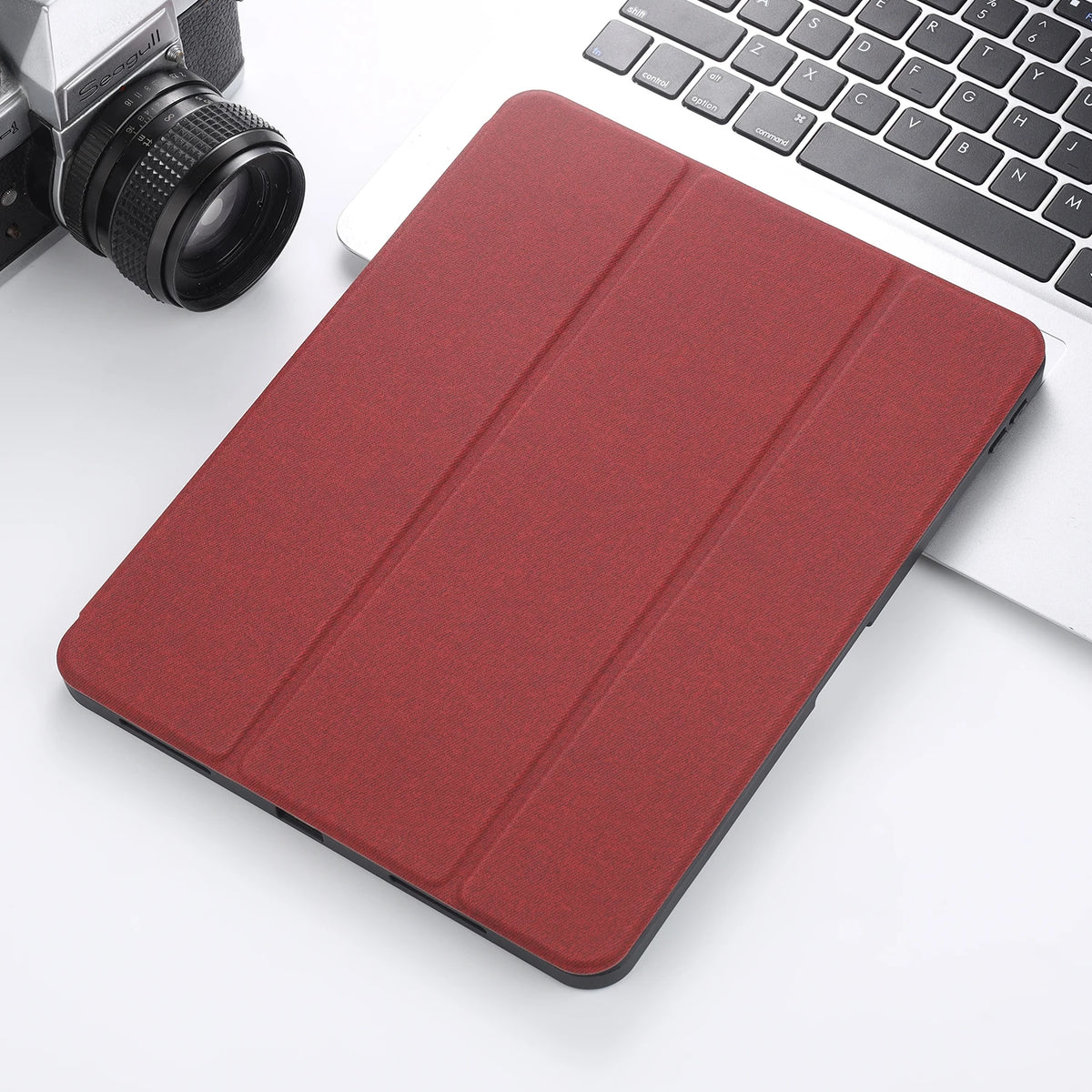 A red retro marbling skin for an iPad Pro placed next to a silver camera and a white laptop keyboard.