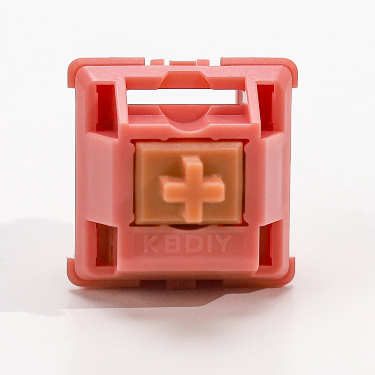 A pink plastic mechanical keyboard switch housing with a light peach-colored switch inside.