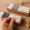 A hand is assembling a vintage wooden stamp seal set for card making, showing letters and numbers.