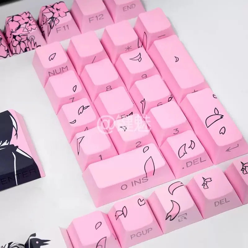 Pink mechanical keycaps featuring a raven and sakura theme arranged on a white surface.