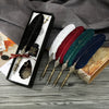 A set of retro calligraphy feather dip pens in various colors displayed in a black gift box on a wooden surface.