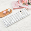 Weiße mechanische Tastatur mit rosa Tastenkappen neben einem Holztray und rosa Verpackung