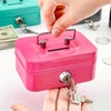A hand is opening a bright pink steel cash box with a key lock and removable tray.