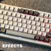 A close-up view of a light gray mechanical keyboard with RGB lighting effects on a dark gray surface.